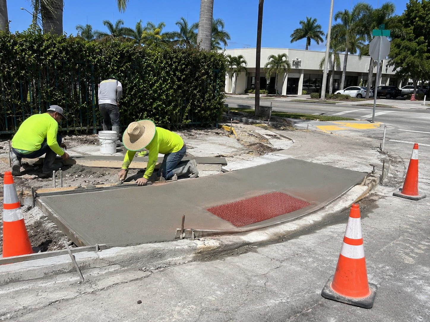 crew installing a curb ramp with a red detectable warning surface in Miami