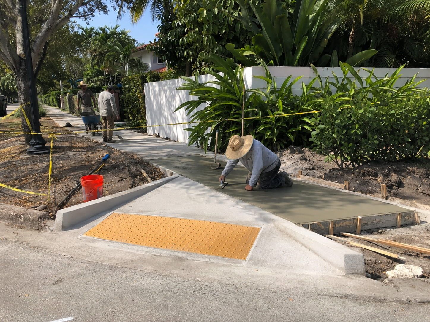 crew finishing a fresh concrete sidewalk and curb ramp in Miami
