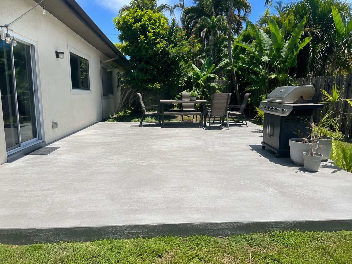concrete patio with dining table and grill in a Miami backyard